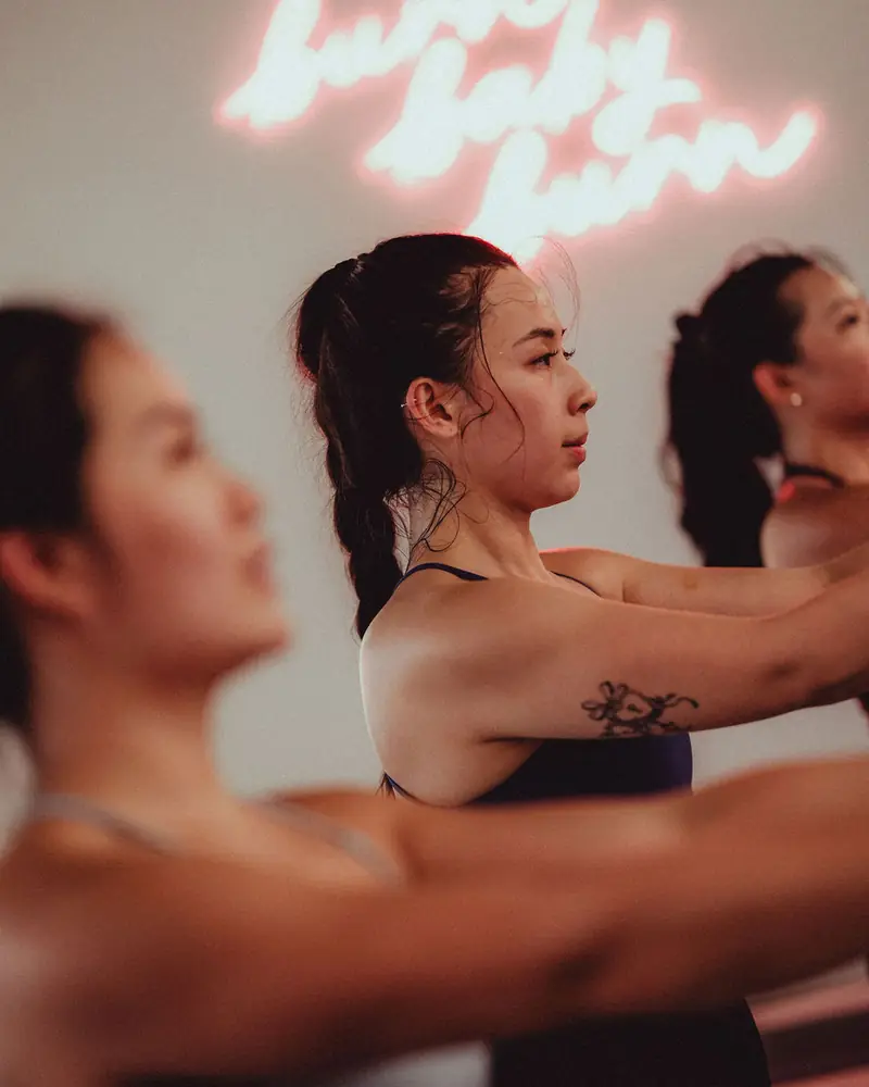 A hot mat class reaching forward under a neon sign