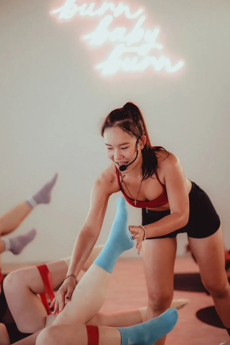A hot mat instructor with a headset helping a client with a band